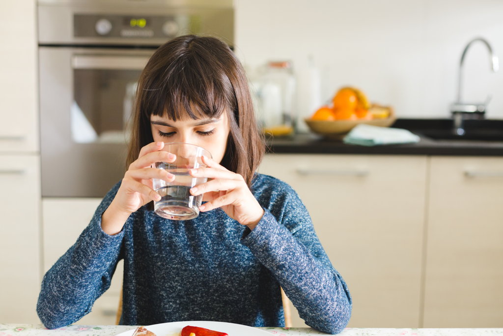 Niña bebiendo agua en la cocina